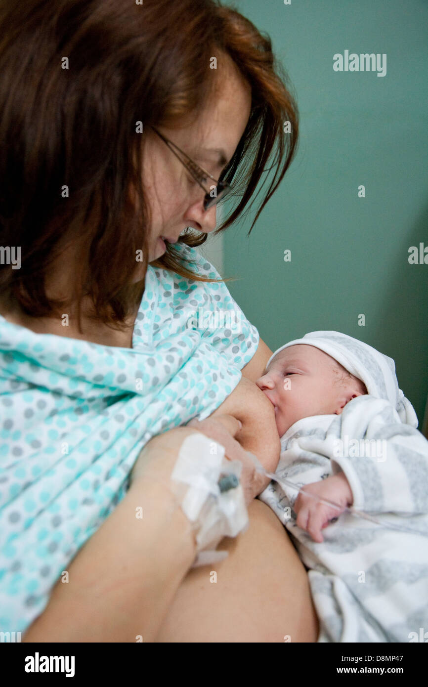 Una donna che ha appena partorito dà il suo bambino che nasce la sua prima alimentazione. Foto Stock