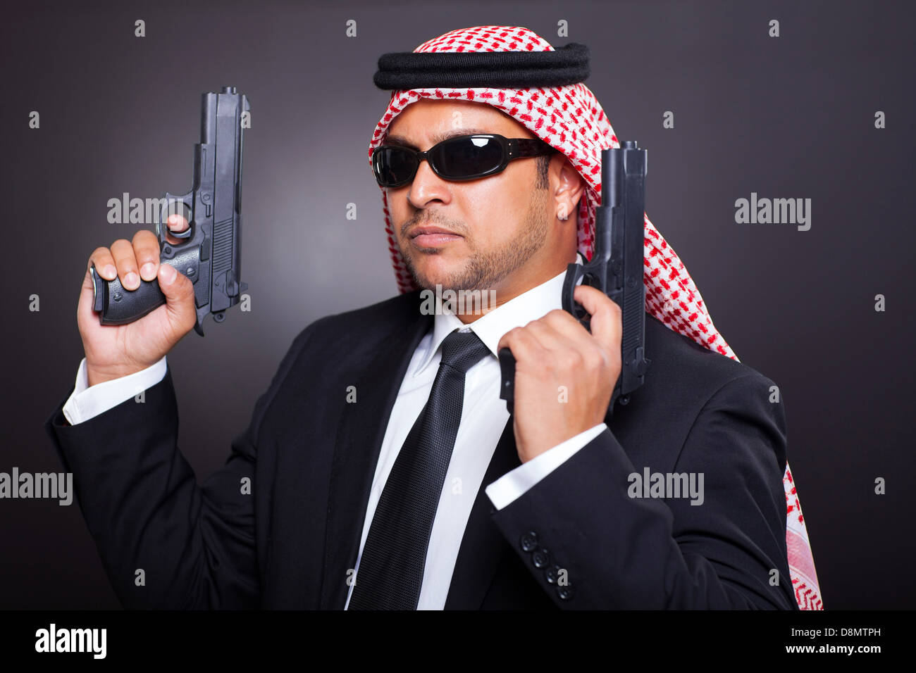 I giovani del medio oriente ponendo hitman con pistole su sfondo nero Foto Stock