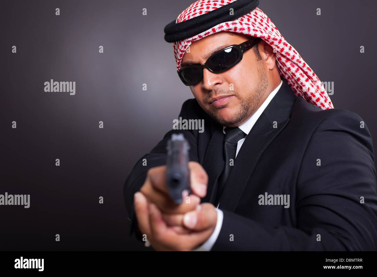 Arabian spy in occhiali da sole azienda pistola su sfondo nero Foto Stock
