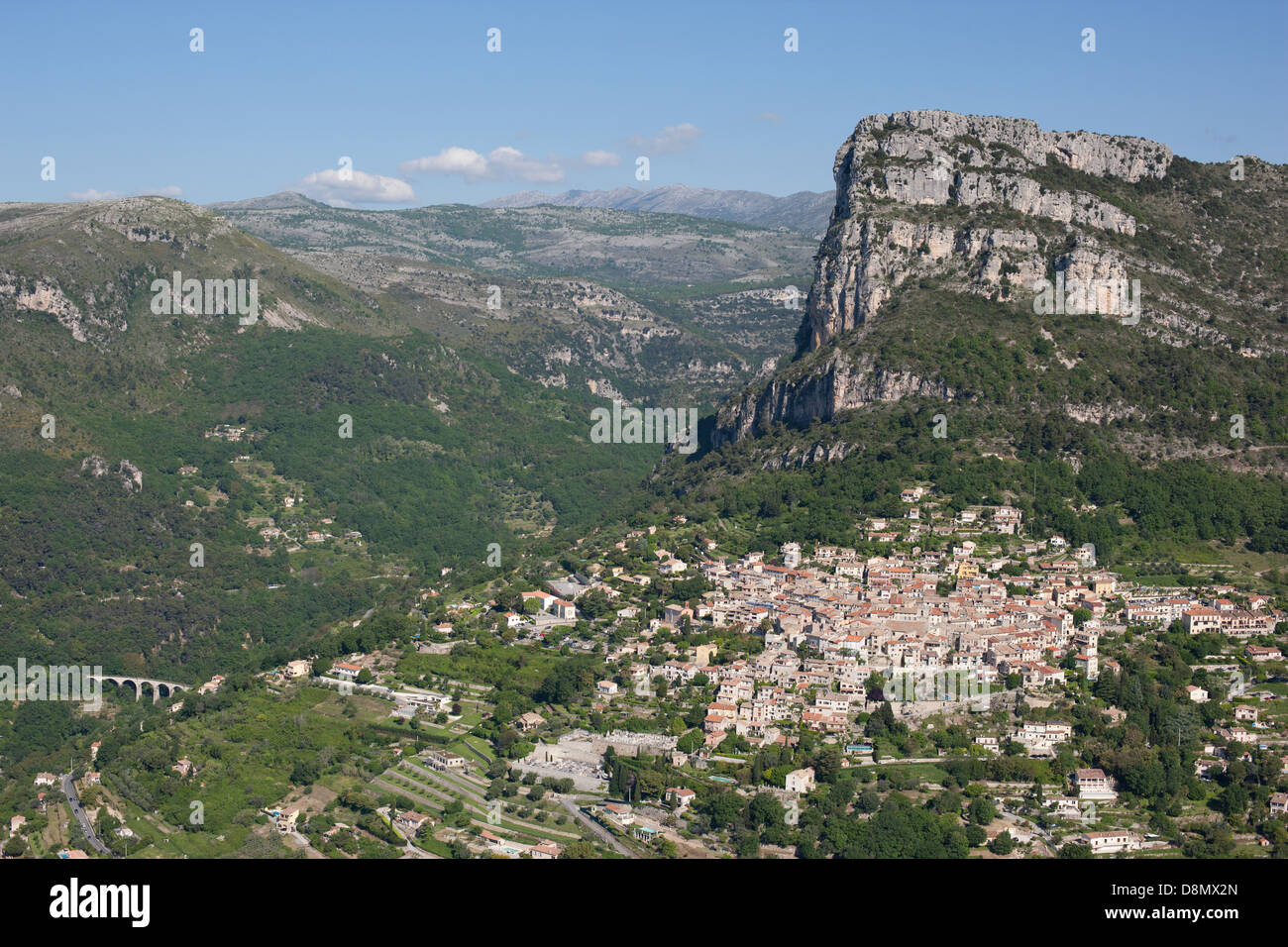 VISTA AEREA. Borgo medievale ai piedi di una massiccia scogliera alta 400 metri. Saint-Jeannet, Costa Azzurra, Alpes-Maritimes, Francia. Foto Stock