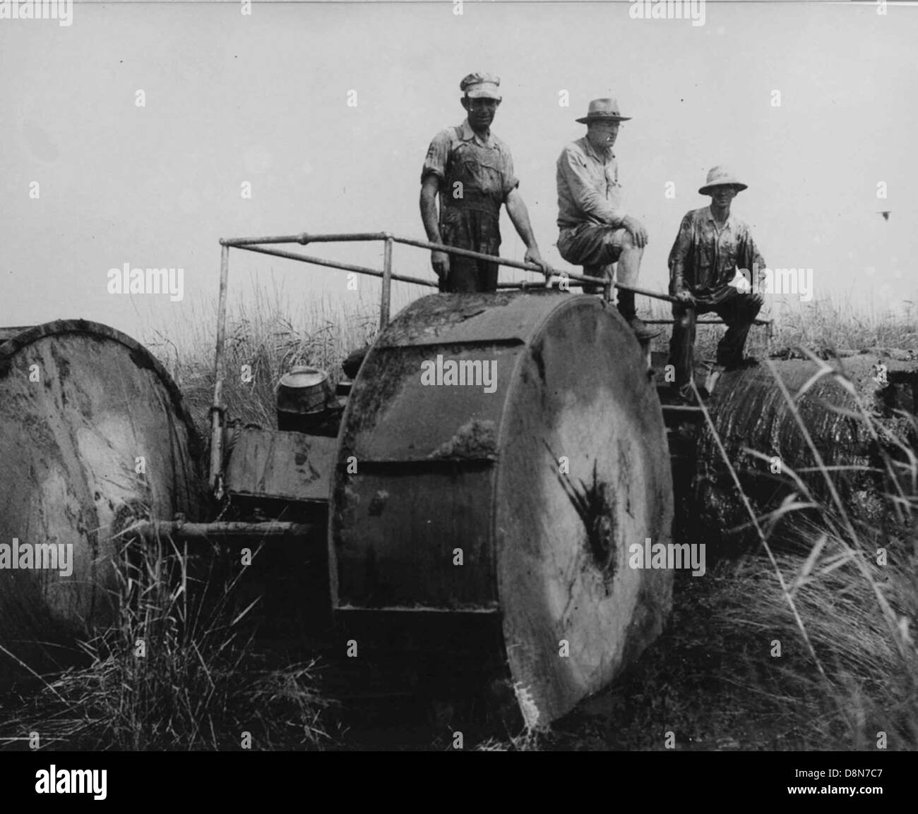 Una foto d'epoca raffigura alcune persone che gestiscono una vecchia macchina per la lavorazione di marmellate. Questa scena storica mostra le prime tecnologie meccaniche e le persone che utilizzano i primi macchinari industriali. Foto Stock