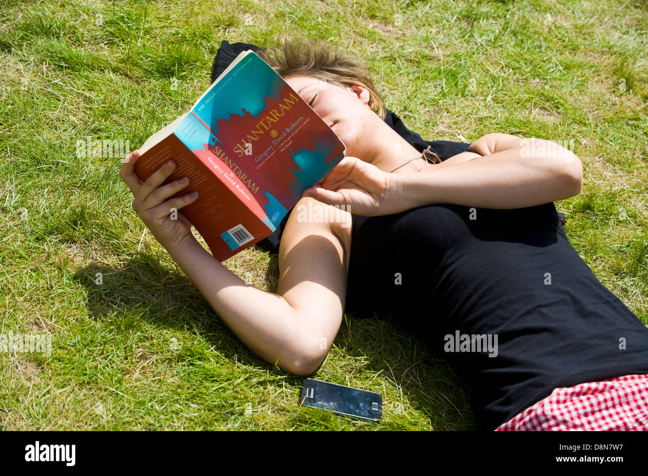 Giovane donna libro lettura sdraiati sull'erba in estate il sole a Hay Festival 2013 Hay on Wye Powys Wales UK Foto Stock