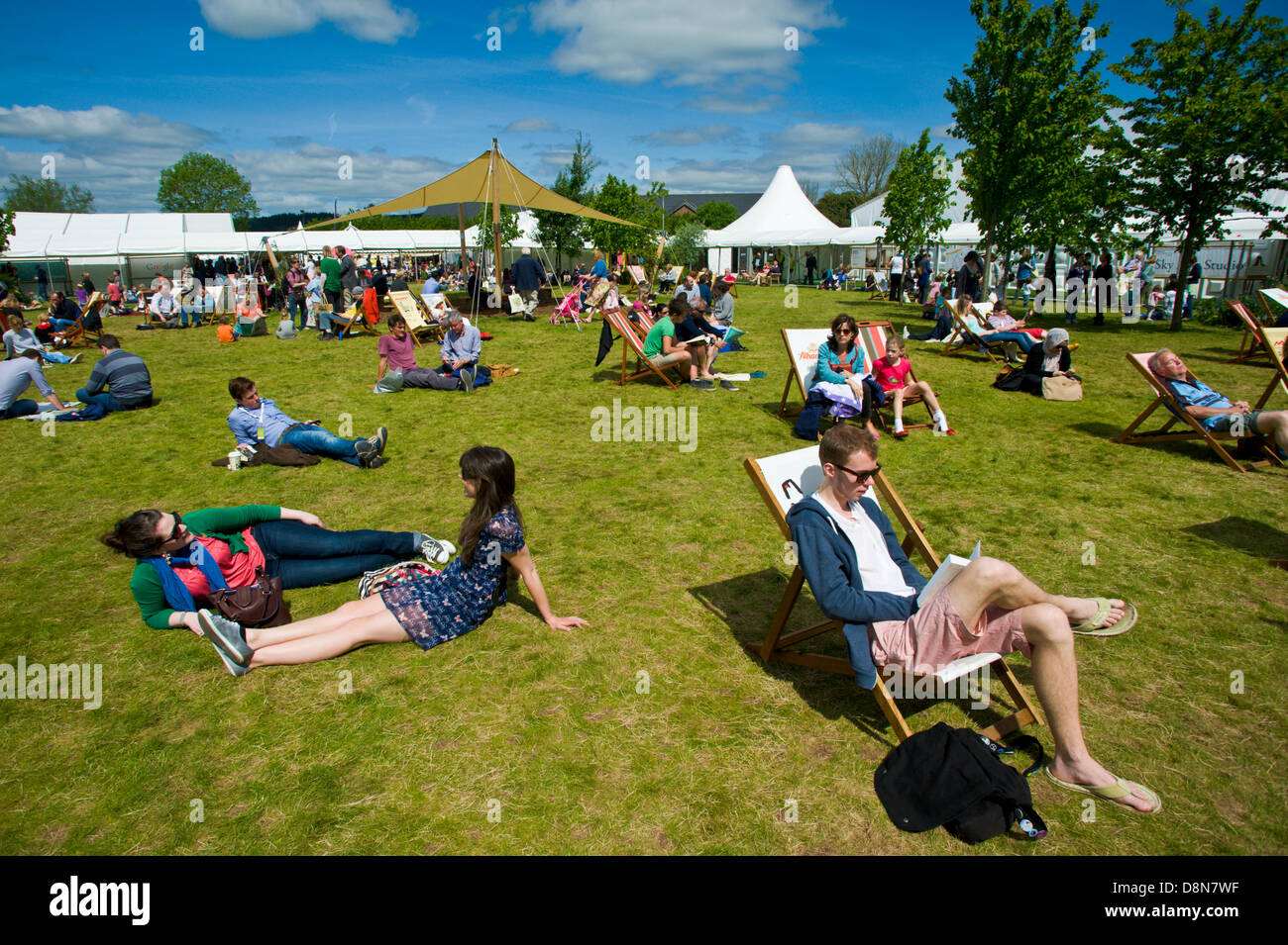 I visitatori godere la calda estate meteo rilassarsi sul prato a Hay Festival 2013 Hay on Wye Powys Wales UK Foto Stock