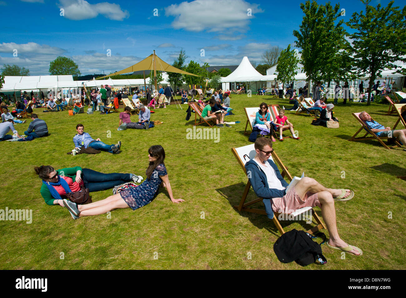 I visitatori godere la calda estate meteo rilassarsi sul prato a Hay Festival 2013 Hay on Wye Powys Wales UK Foto Stock