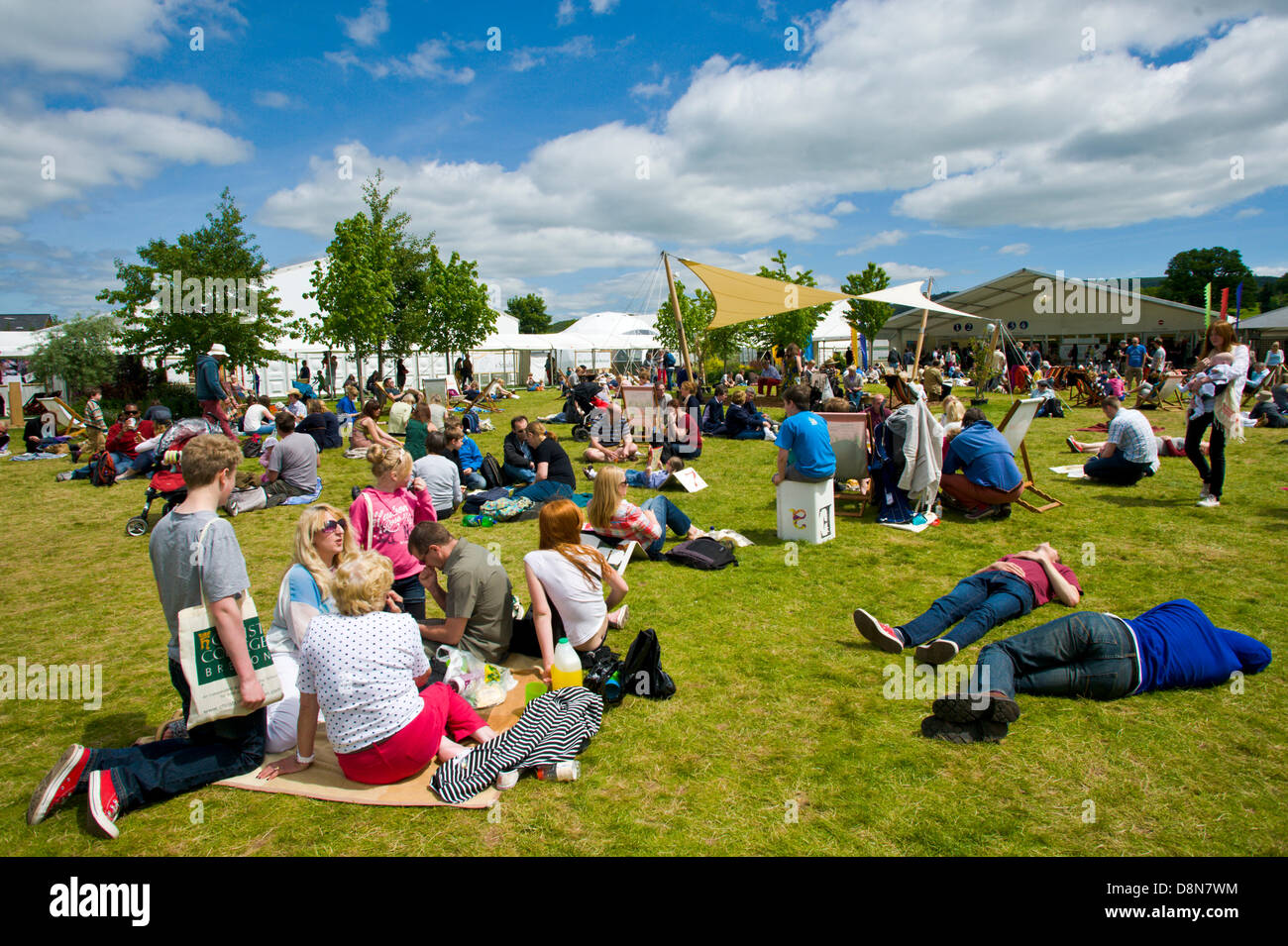 I visitatori godere la calda estate meteo rilassarsi sul prato a Hay Festival 2013 Hay on Wye Powys Wales UK Foto Stock