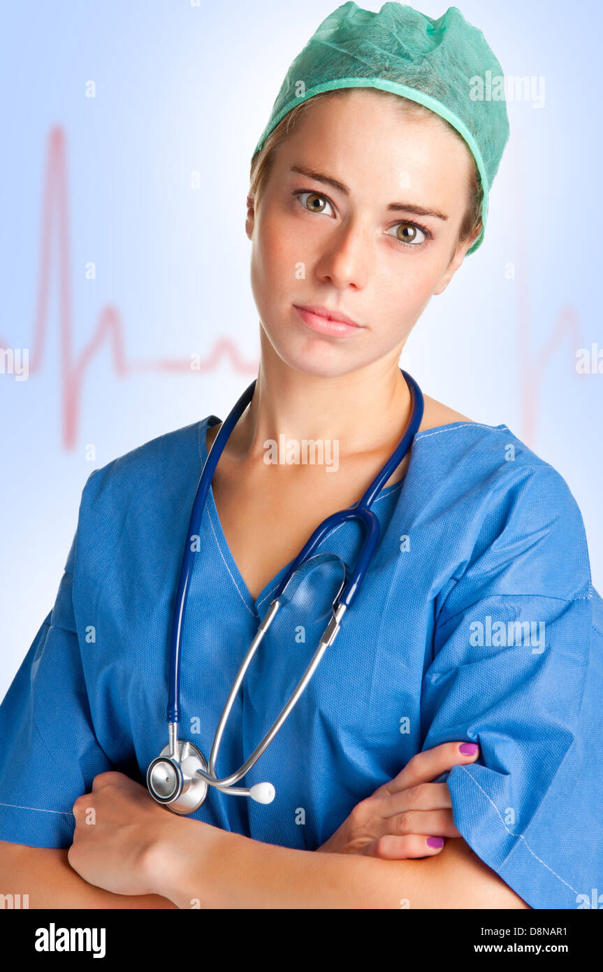 Giovani donne chirurgo con scrubs e uno stetoscopio, con un grafico EKG dietro di lei Foto Stock