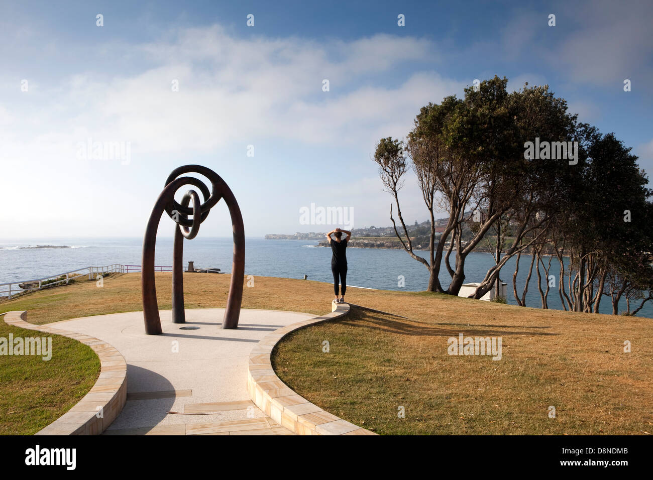 Un pareggiatore guarda nell'oceano mentre in piedi accanto al memoriale di Bali scultura in Coogee a Sydney in Australia Foto Stock