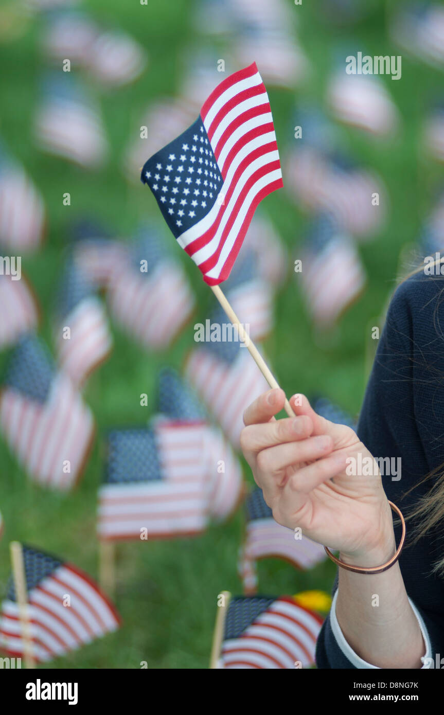 Agitando a mano piccole United States Flag con il campo delle bandiere dietro. Foto Stock