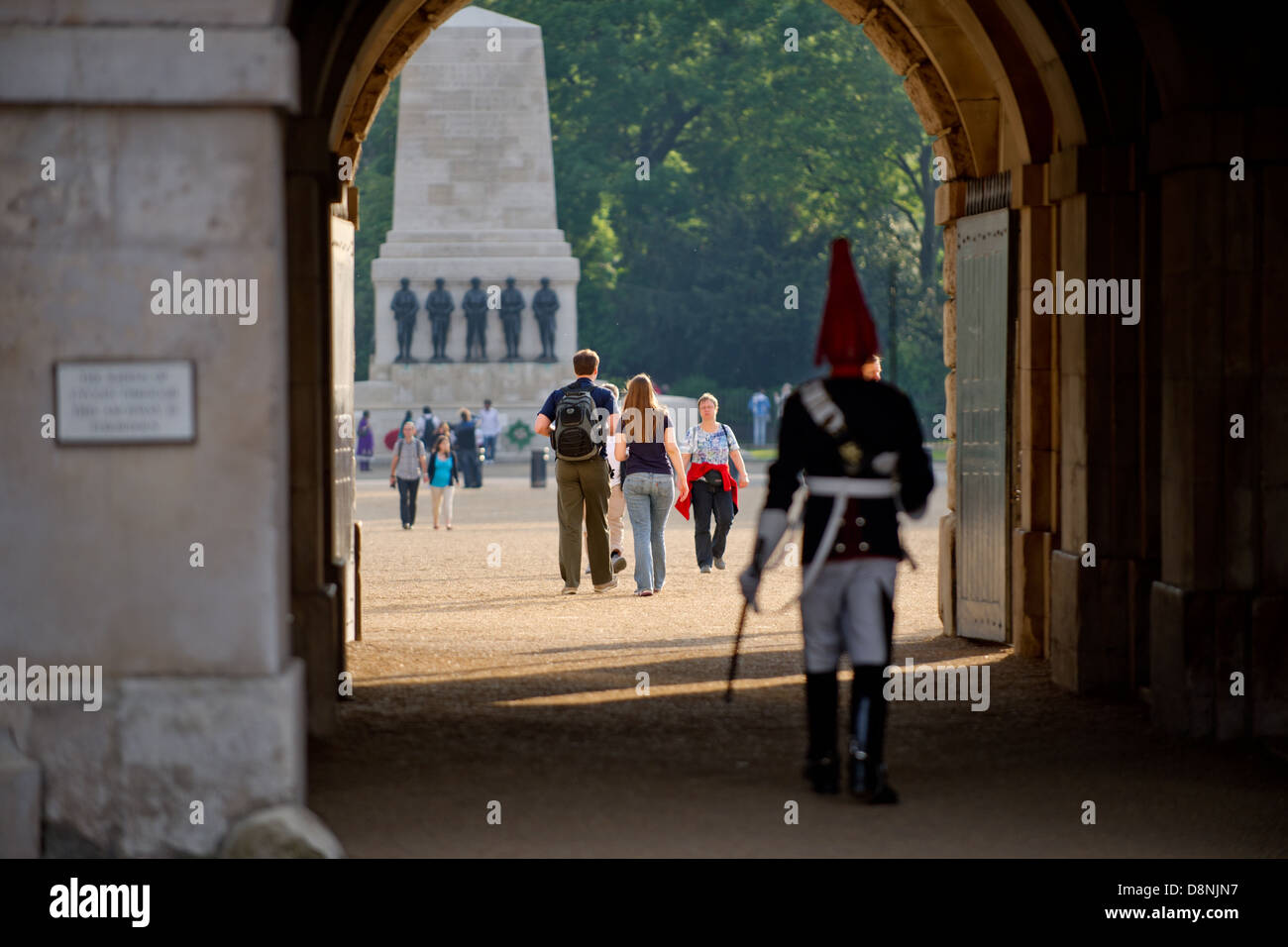 Un giovane a piedi attraverso la sfilata delle Guardie a Cavallo, Londra, Regno Unito, con una resa uniforme Horse Guard in primo piano. Foto Stock