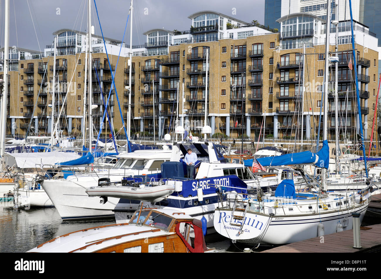 Uomo in piedi su una barca presso San Katharine Docks, con vista della marina e si affaccia su moderni appartamenti / appartamenti. Londra, Inghilterra, Regno Unito. Foto Stock