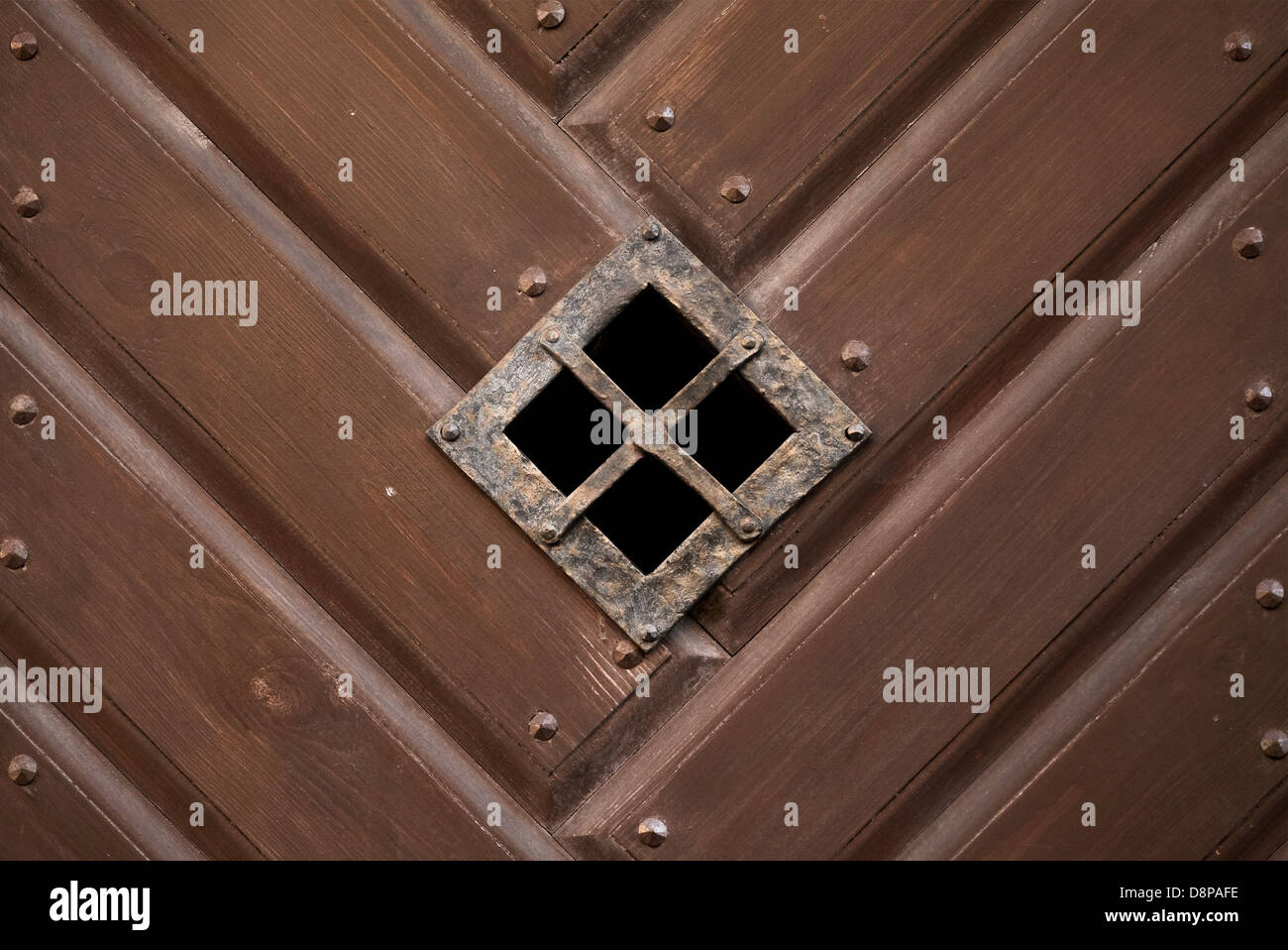 Piccola finestra di visualizzazione con griglia nel vecchio brown porta in legno Foto Stock