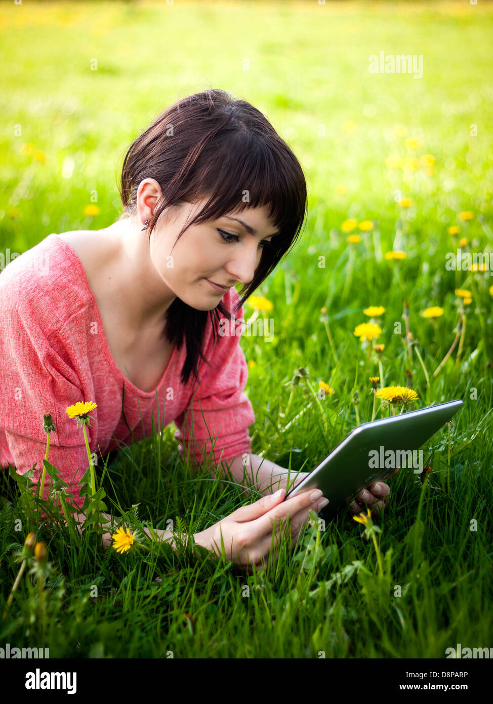 Giovane donna utilizzando tablet posa all'aperto sull'erba Foto Stock