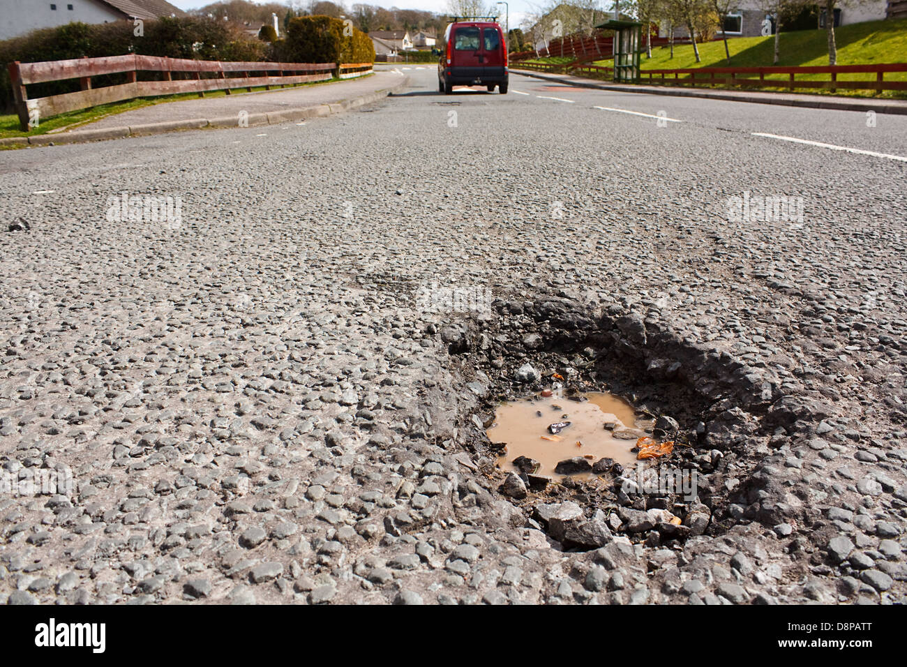 Grande profonda buca un esempio di cattiva manutenzione stradale dovuta alla riduzione locale Consiglio bilanci di riparazione Foto Stock