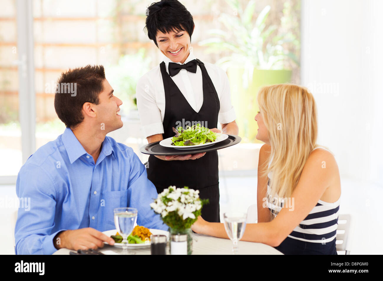 Felice cameriera serve clienti in ristorante Foto Stock