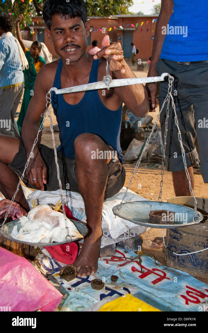 Fornitore indiano la pesatura di un pollo a un mercato a cielo aperto nel villaggio di Moca, Madya Pradesh, India Foto Stock