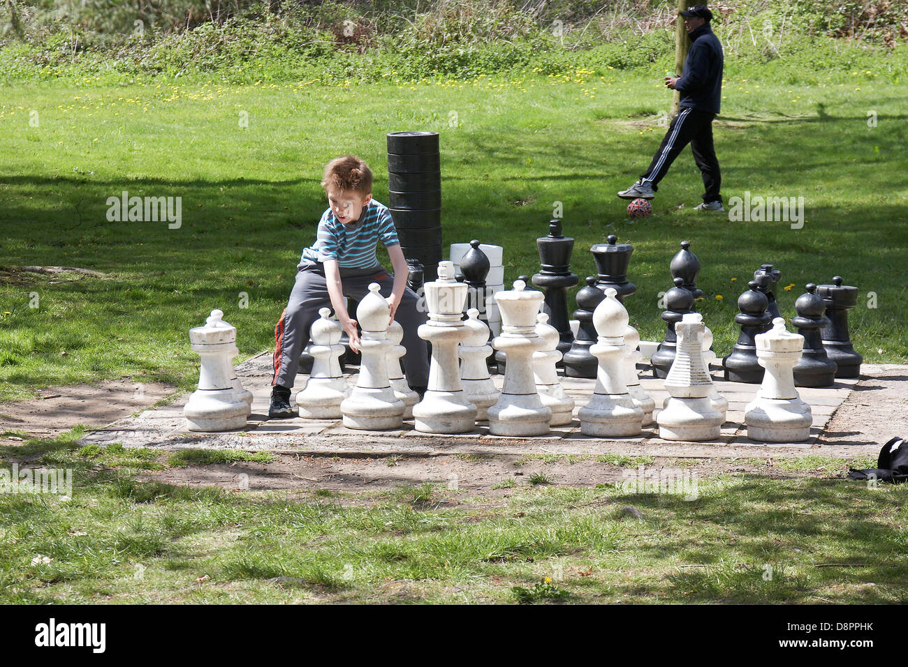 Giovane ragazzo giocando a scacchi da lui stesso a Margam country park, Wales, Regno Unito. Foto Stock