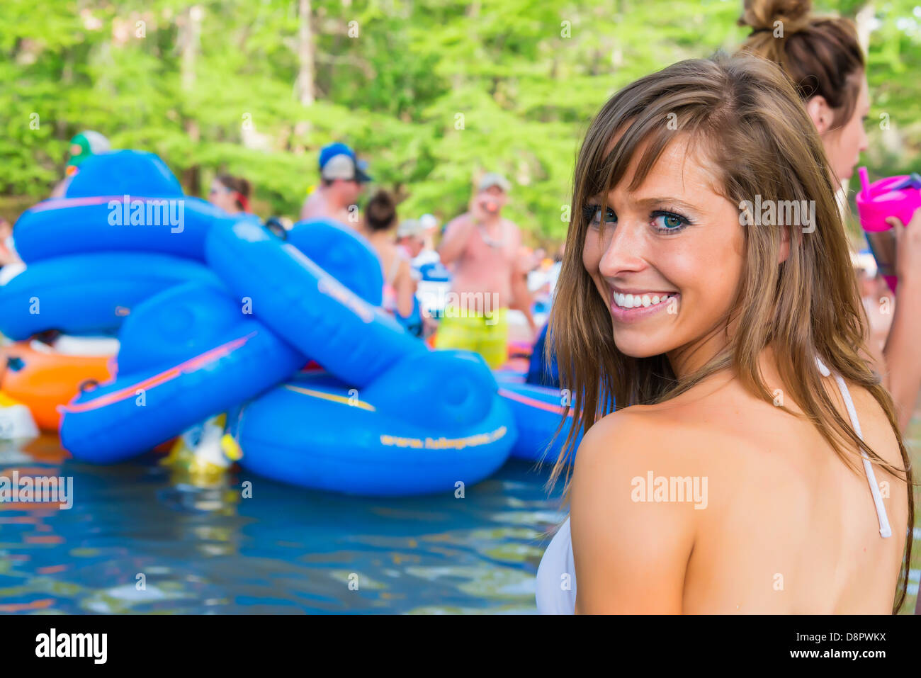 Giovane donna (25 Caucasica) al Frio River, persone Tubing sul fiume in background, Concan, Texas, Stati Uniti d'America Foto Stock