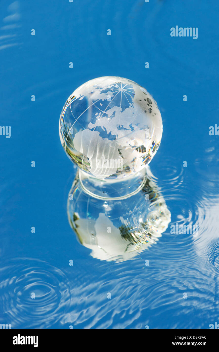 Crystal globo di vetro / Massa / mondo su uno specchio con acqua che riflette il cielo blu Foto Stock