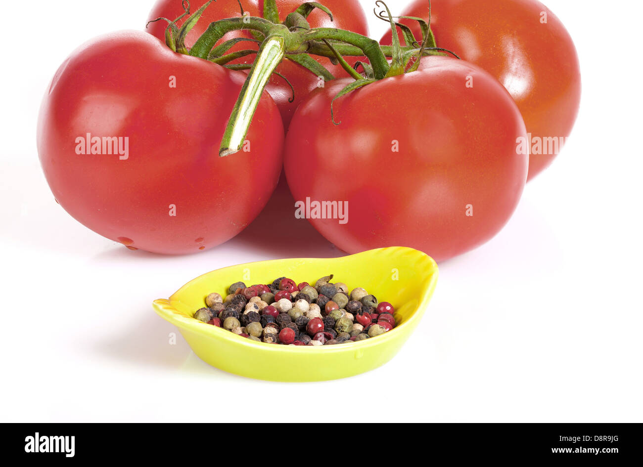 Freschi pomodori a grappolo con una tazza di chicchi di pepe isolato su sfondo bianco Foto Stock