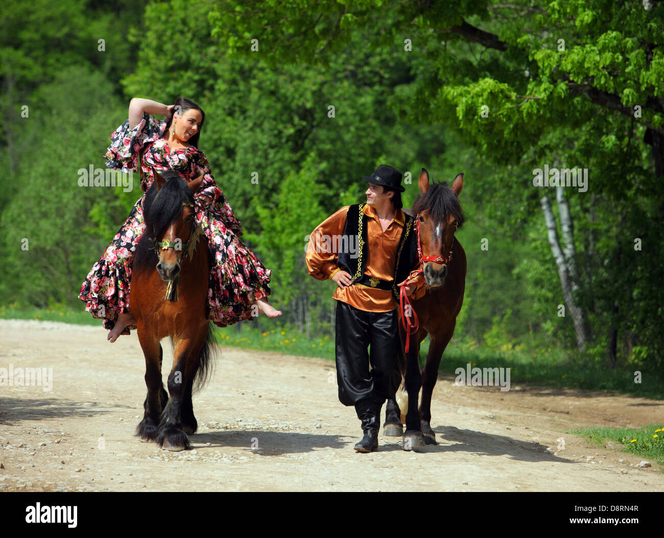 Roma e la donna gitana a piedi attraverso il bosco con i cavalli Foto Stock