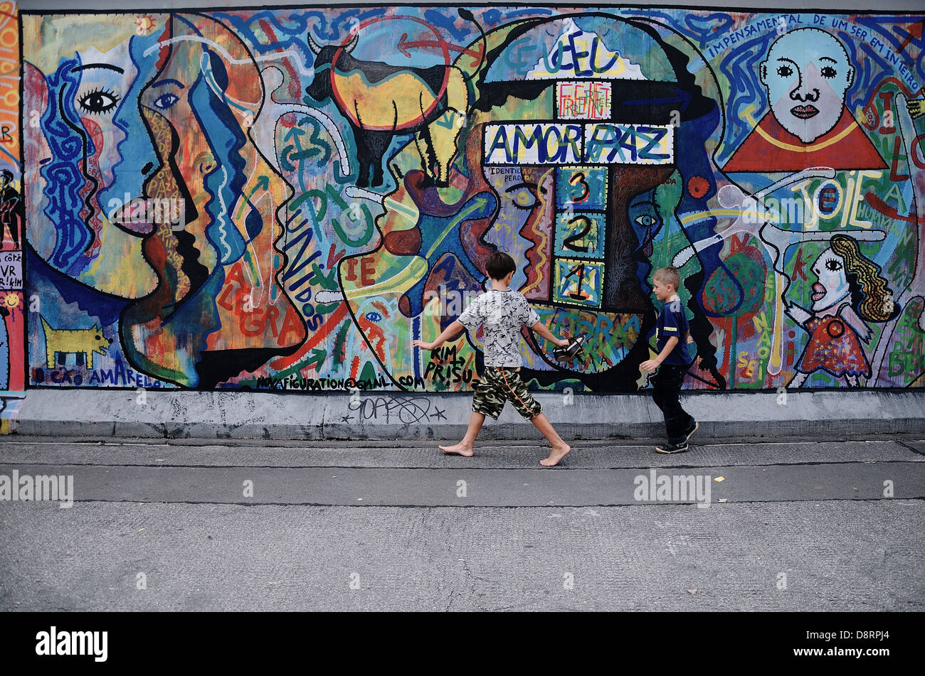 Ragazzi giocare nella parte anteriore del rimanente muro di Berlino. Berlino, Germania Foto Stock