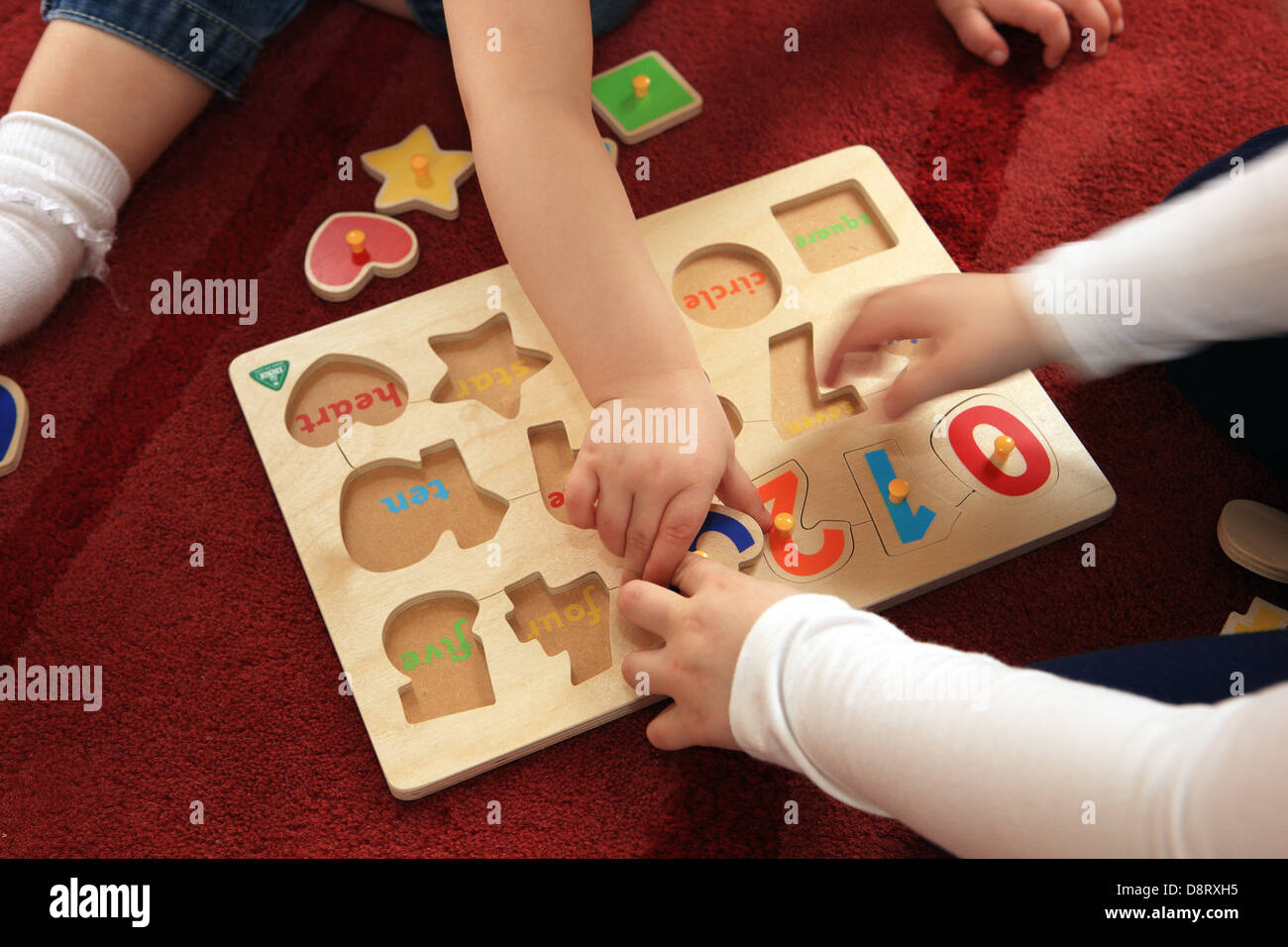 Bambini che giocano sul pavimento con i numeri in legno e forme gioco Foto Stock