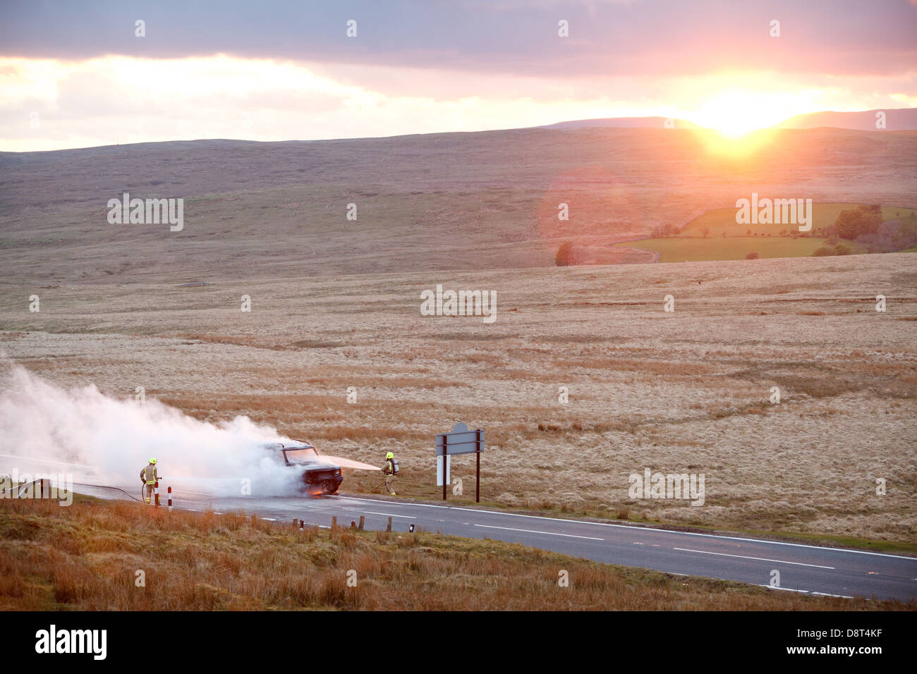 Un landrover discovery prende fuoco sulla A4059 tra Hirwaun e Brecon. Il veicolo brucia come il sole tramonta sulle colline. Foto Stock