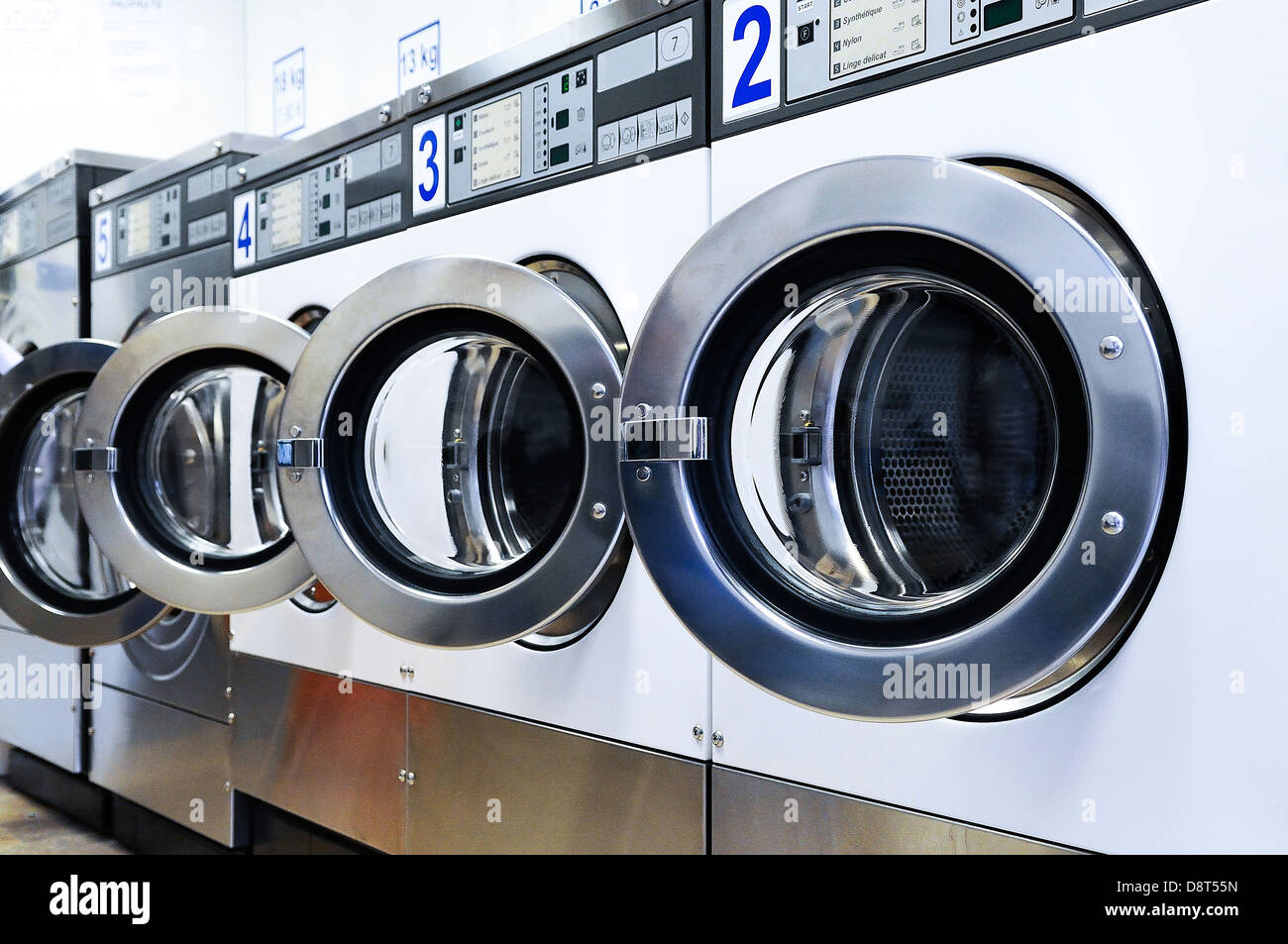 Una fila di macchine lavatrici industriali in una lavanderia pubblica Foto Stock