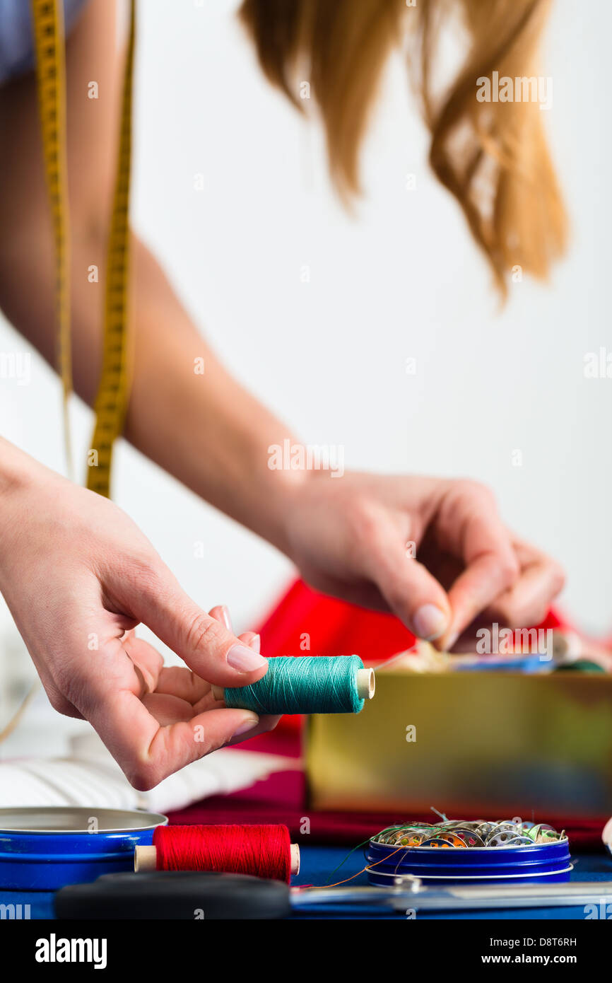 Freelance - adattare o designer che lavora con diversi utensili, come cotone bobine, spole, e tessuti colorati Foto Stock