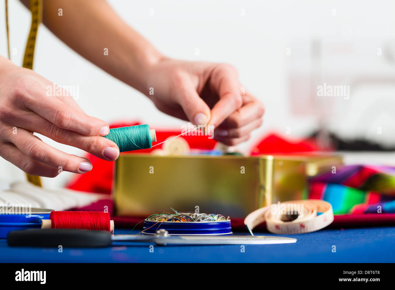 Freelance - adattare o designer che lavora con diversi utensili, come cotone bobine, spole, e tessuti colorati Foto Stock