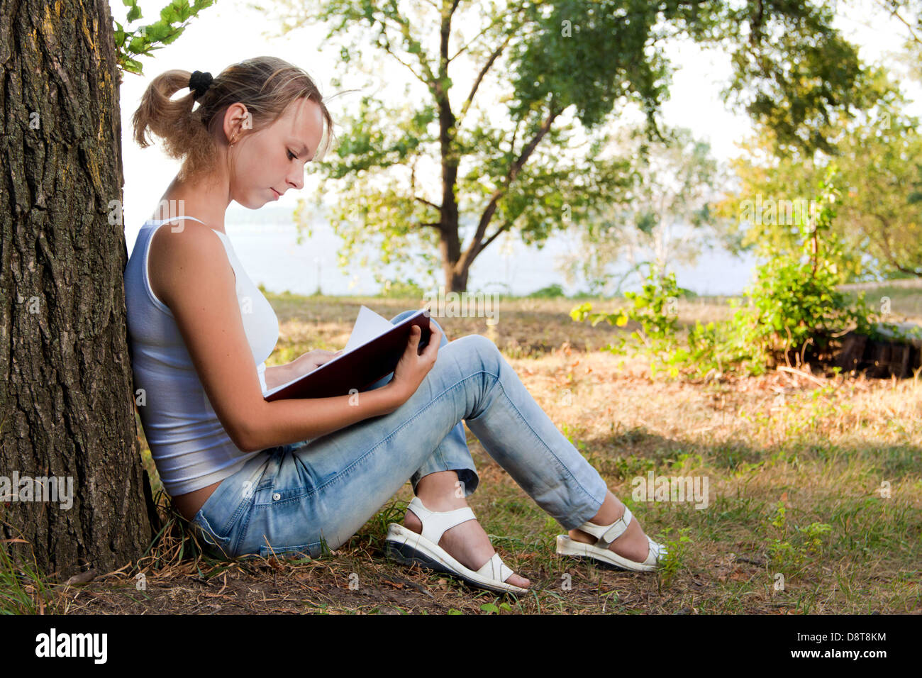 Giovane donna libro di lettura nel parco Foto Stock