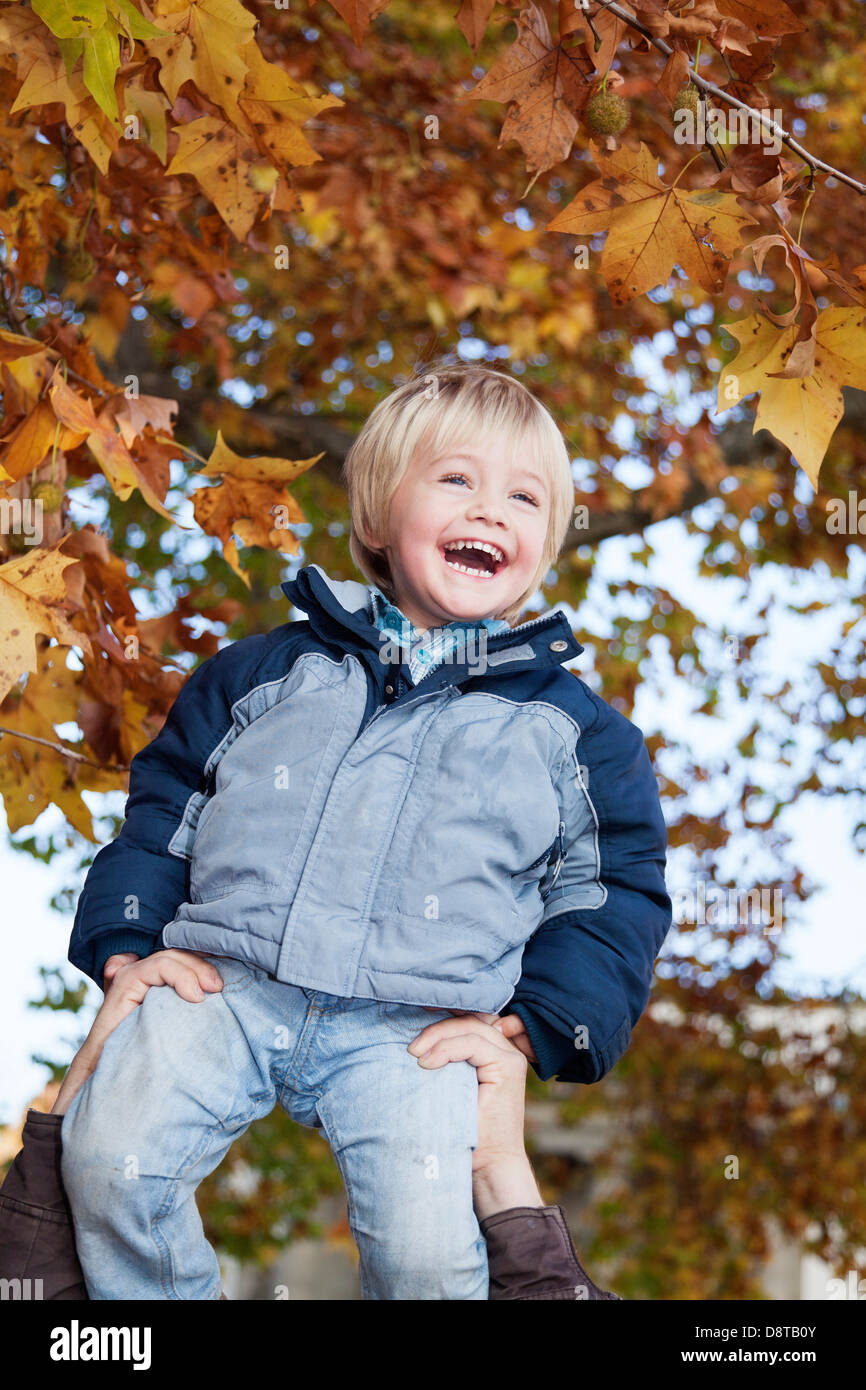 Tre anno-vecchio ragazzo godendo sollevato dal suo padre Foto Stock