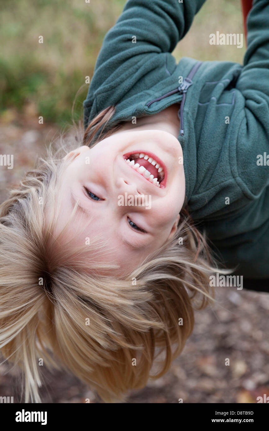 4 anno-vecchio ragazzo appeso a testa in giù su un altalena Foto Stock