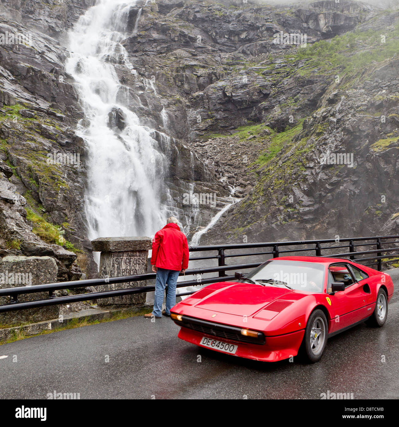 Turistico con auto sportiva su strada Trollistigen con cascata Stigfossen, Norvegia Foto Stock