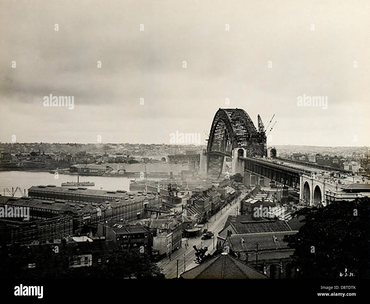 Questa fotografia in bianco e nero del 1931 cattura l'iconico Sydney Harbour Bridge da Lower Fort Street. L'immagine fa parte dell'archivio State Records NSW, che mostra lo sviluppo storico di uno dei monumenti più famosi dell'Australia. Foto Stock