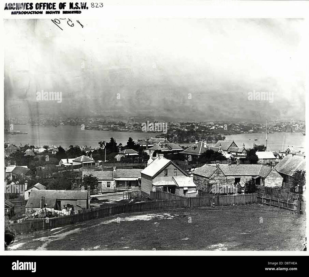 Questa fotografia in bianco e nero del porto di Sydney cattura l'iconica vista del porto, con lo skyline della città e le case lungo il lungomare. L'immagine mostra il paesaggio marittimo e urbano di Sydney, nel nuovo Galles del Sud. Foto Stock