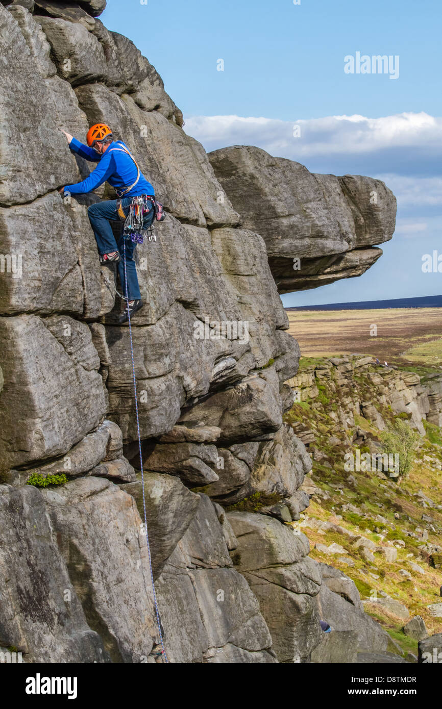 Tradizionale rock scalatore persona salendo una roccia arrampicata a Stanage Edge, Regno Unito Foto Stock