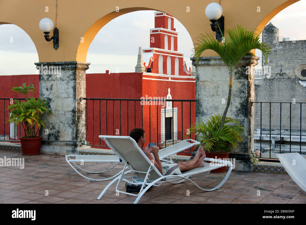 Giovane uomo utilizzando un telefono intelligente durante i momenti di relax sulla terrazza dell'Hotel Caribe in Merida, Messico Foto Stock