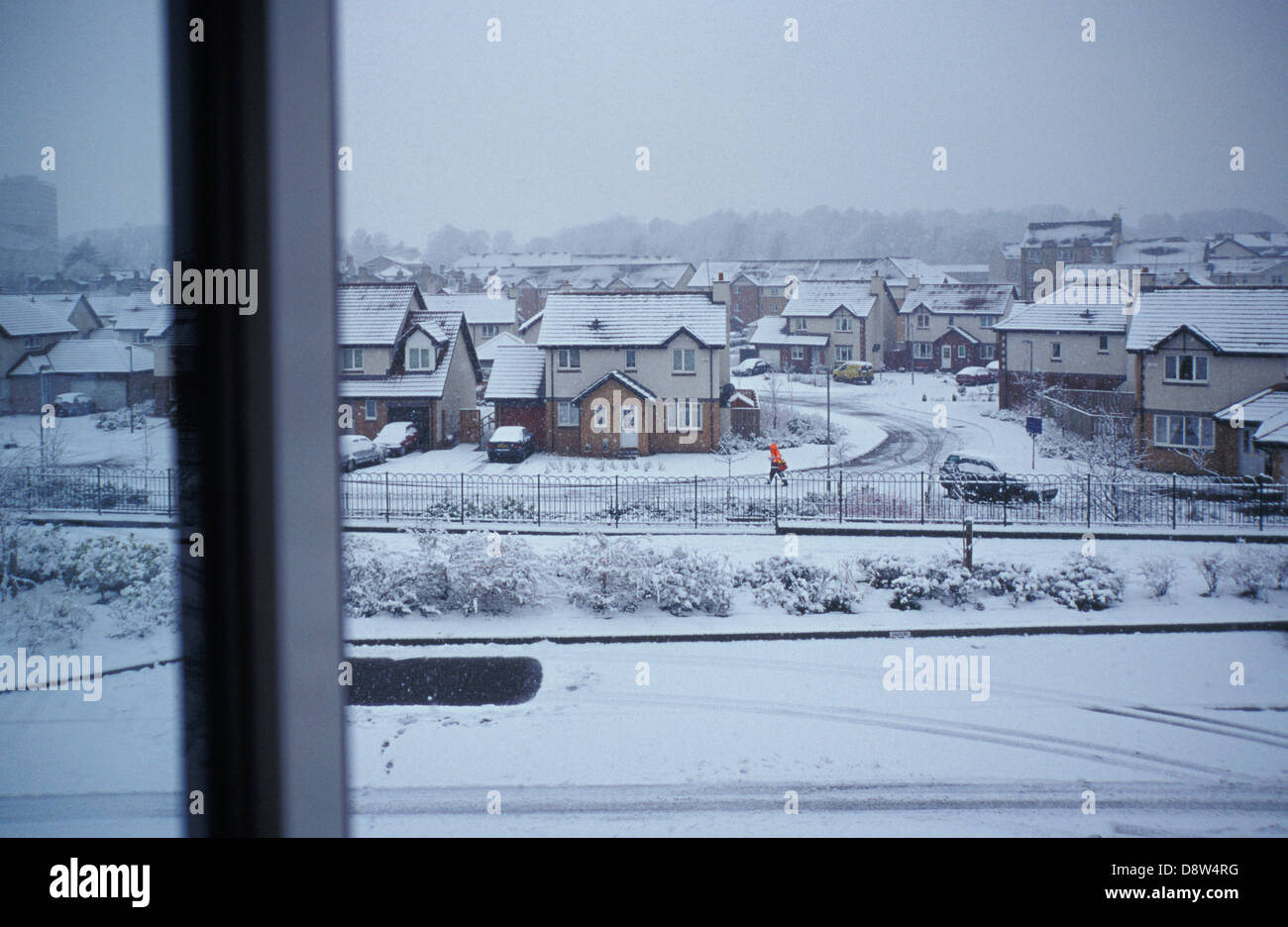 Suburban case e strade in snow visto da una finestra superiore, portalettere facendo il suo giro, Paisley, Scozia Foto Stock