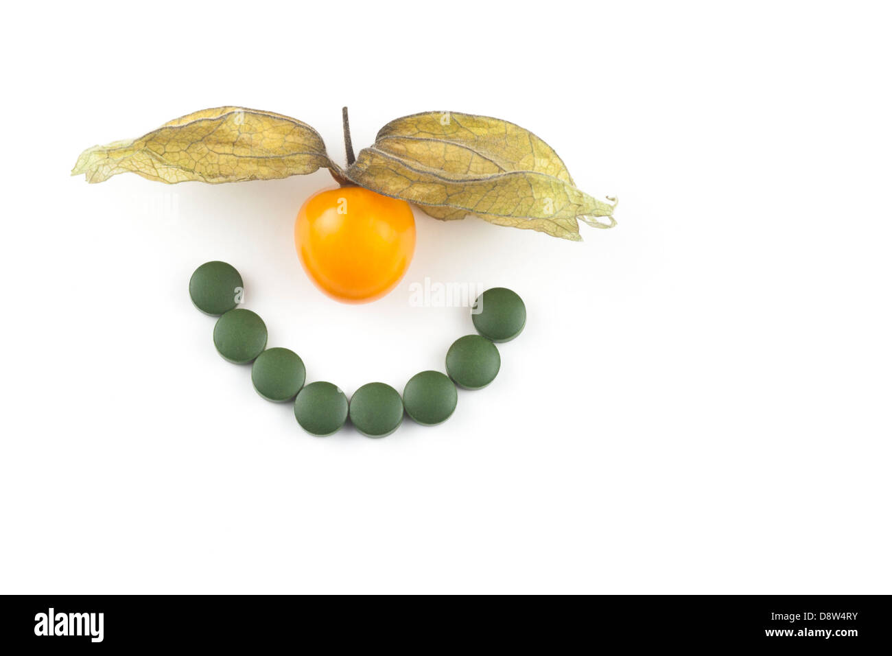 Fresche e dorate di Berry (Physalis peruviana) e Chlorella compresse disposti in un sorriso. Foto Stock