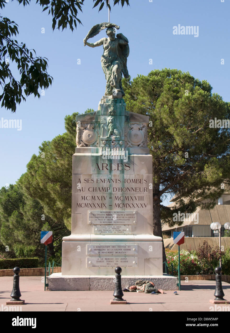 Monumento ai caduti in guerra con un uomo addormentato sul marciapiede in fondo, Arles, Francia Foto Stock