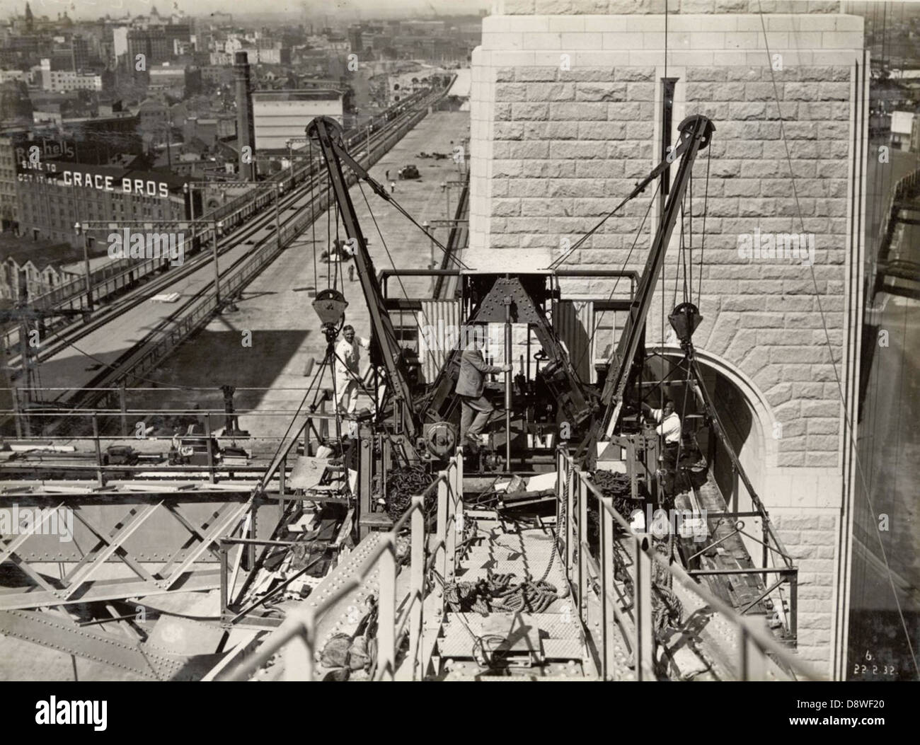 Questa immagine storica mostra una gru e una messa in scena sulla corda superiore del Sydney Harbour Bridge. Preso durante la sua costruzione, mette in risalto le complesse tecniche ingegneristiche e di ponteggi utilizzate per costruire il ponte iconico. L'immagine offre uno sguardo sullo sforzo monumentale necessario per costruire uno dei monumenti più famosi dell'Australia. Foto Stock