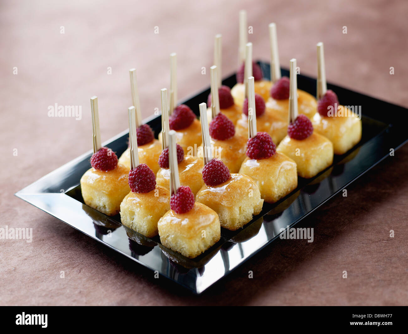 Vassoio di mini square vaniglia e lampone babà per un cocktail da Dalloyau Foto Stock