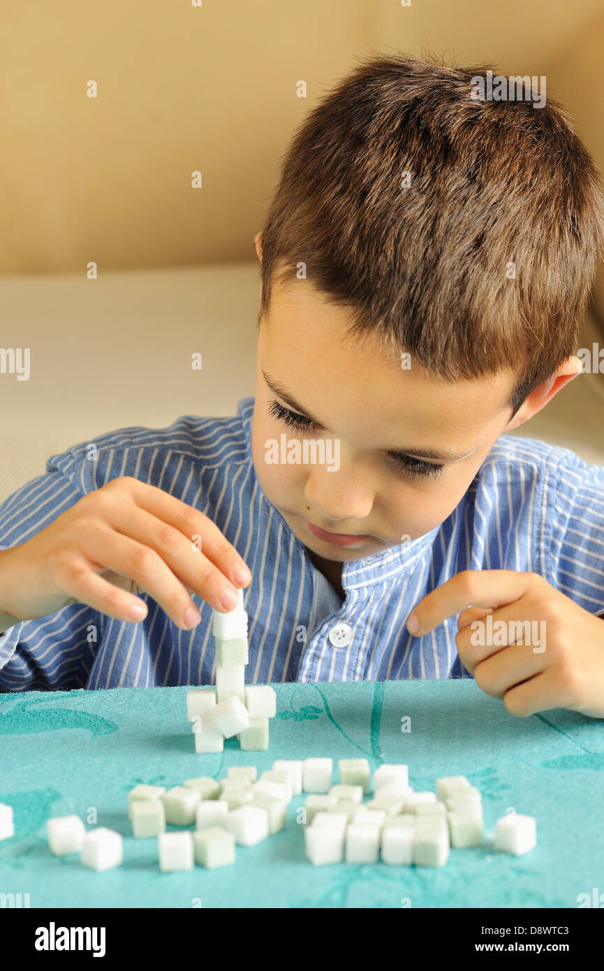 Giovane ragazzo giocando con colorato zollette di zucchero Foto Stock