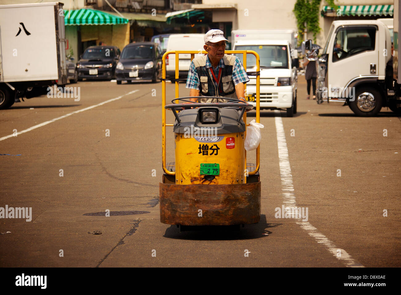 Giapponese di mezza età uomo alla guida di un carrello a motore presso il parcheggio del mercato del pesce Tsukiji a Tokyo Foto Stock