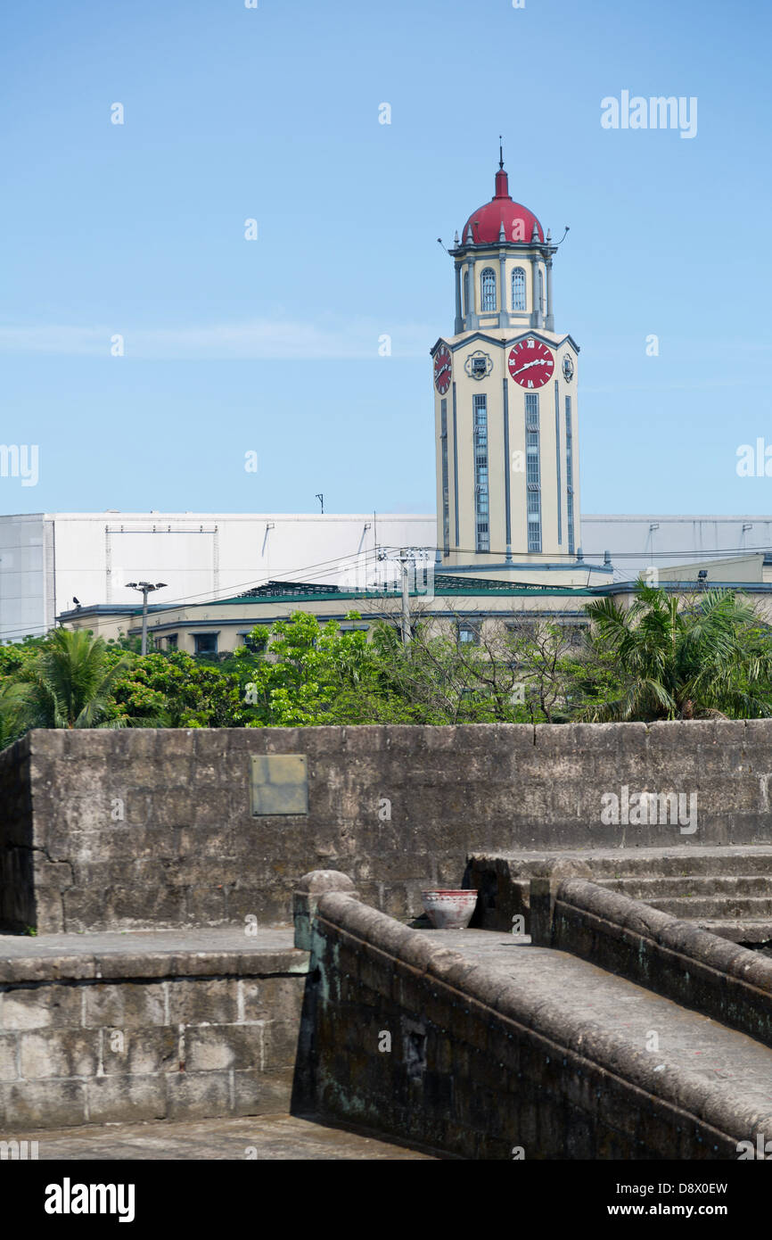 Vista su una torre orologio oltre le mura della città di Intramouros a Manila nelle Filippine Foto Stock