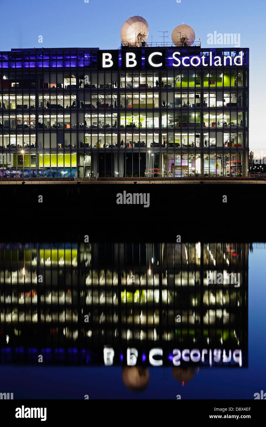 Il quartier generale illuminato della BBC Scotland su Pacific Quay si rifletteva nel fiume Clyde al tramonto, Glasgow, Scozia, Regno Unito Foto Stock