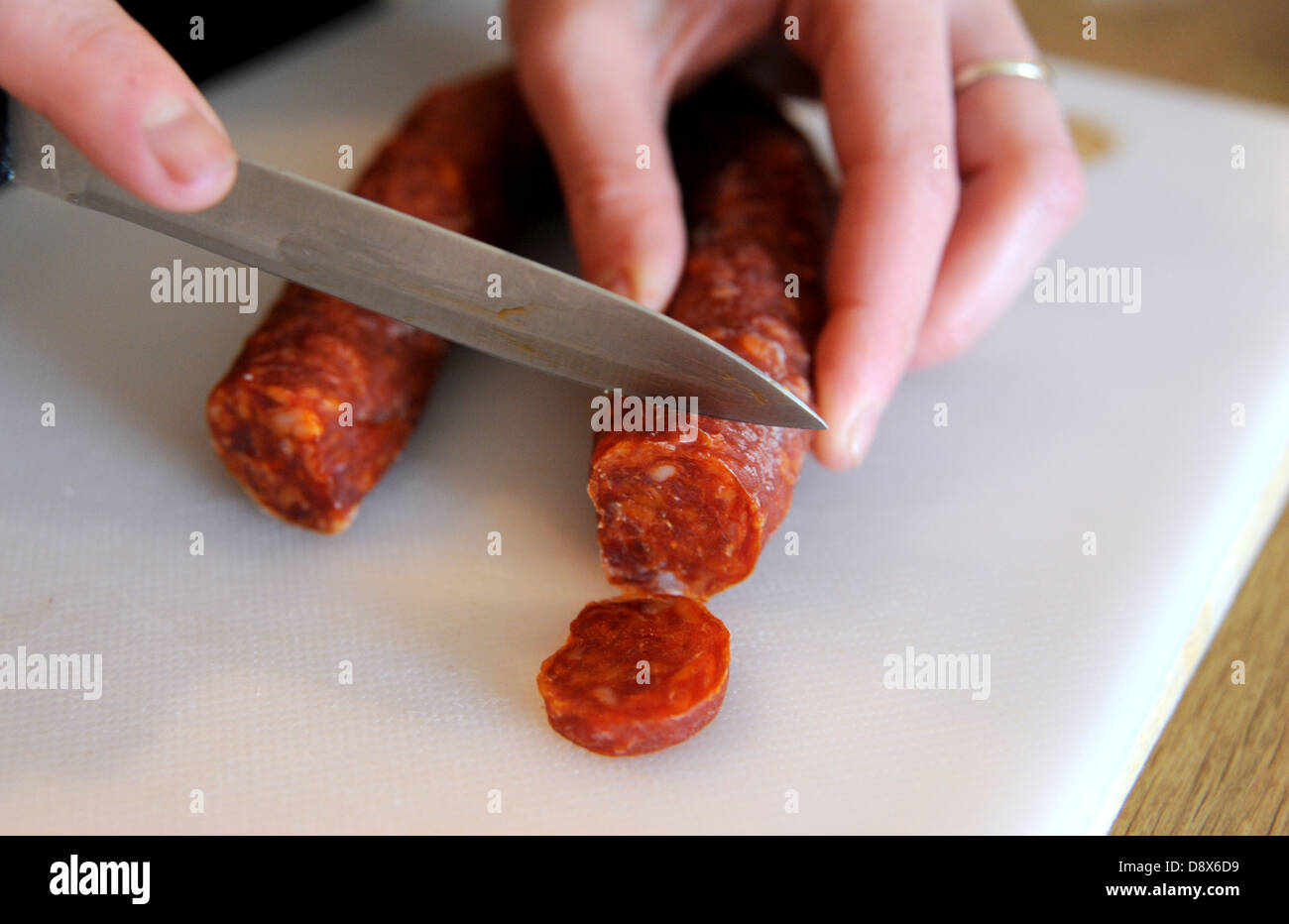 Chiusura del coltello affilato tagliare le fette di salsiccia tipo chorizo spagnolo Foto Stock