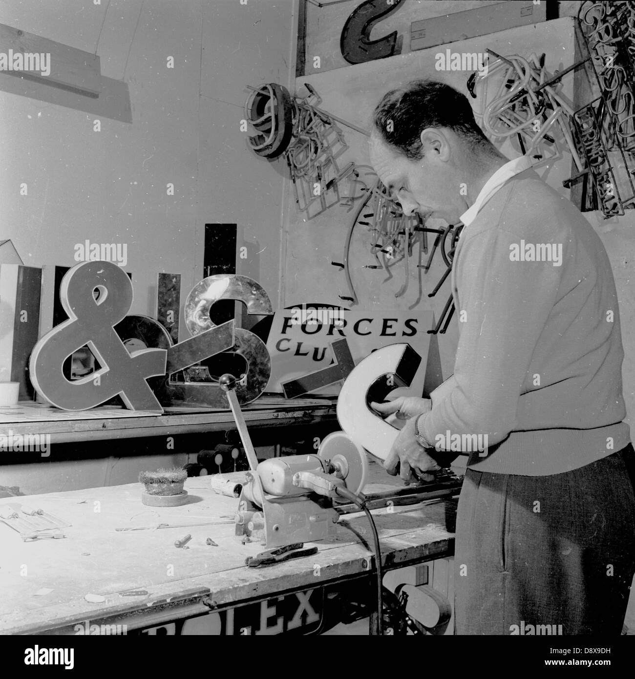 Foto storiche da anni cinquanta di un uomo in officina rendendo le insegne al neon. Foto Stock