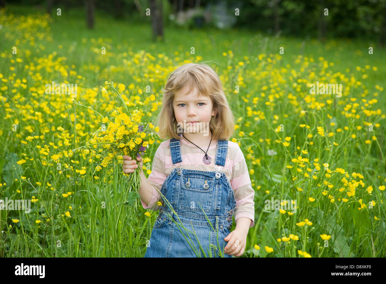 Quattro anni di ragazza con un mazzo di fiori su un prato in primavera Foto Stock